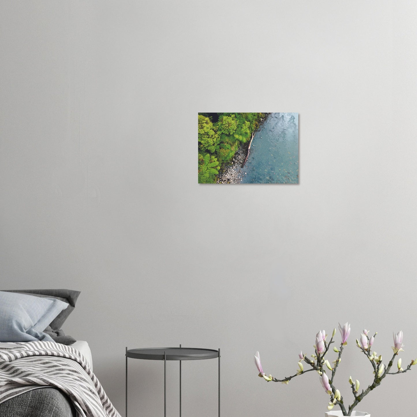 Artwork of native bush and a riverbank viewed from above, with driftwood resting at the water’s edge.