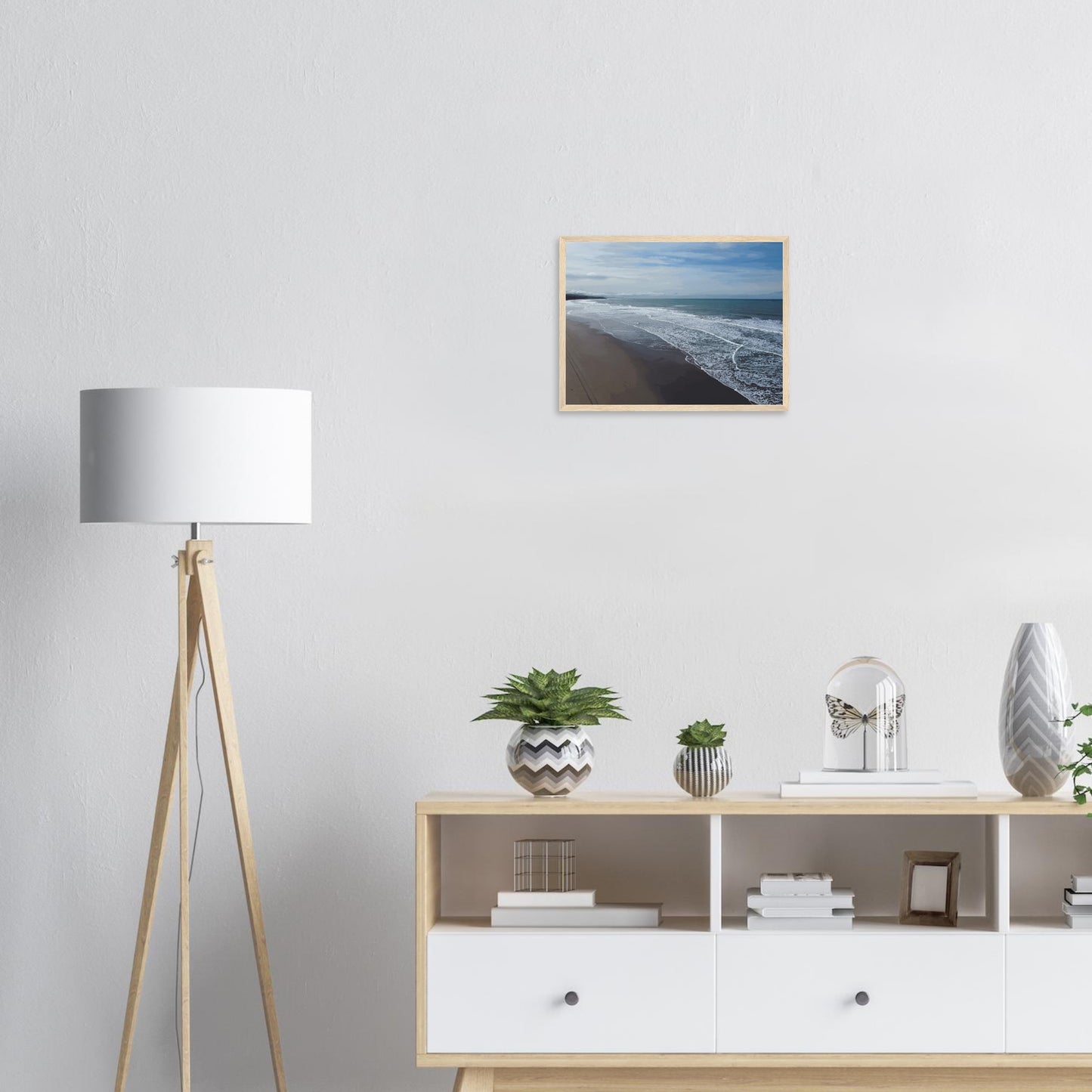 Soft, muted tones of sand, seafoam, and sky blend together in a calming composition, highlighting the natural rhythm of waves lapping the shore.
