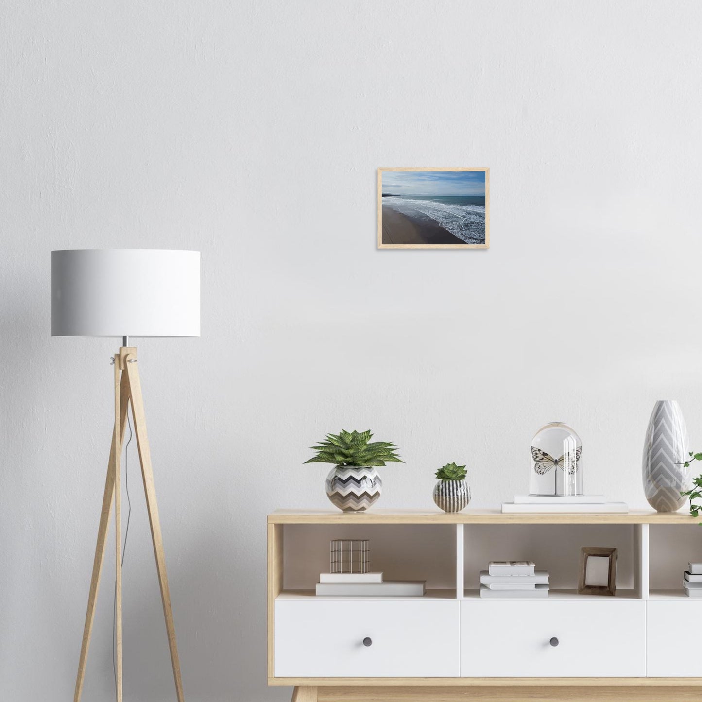 Soft, muted tones of sand, seafoam, and sky blend together in a calming composition, highlighting the natural rhythm of waves lapping the shore.