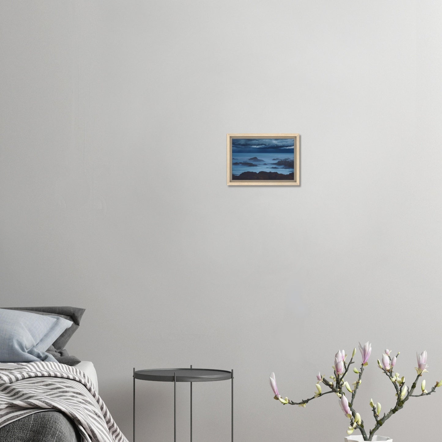Deep navy and steel-blue tones sweep across a moody sky, while waves crash and swirl around jagged rocks, softened by a misty, dreamlike haze.