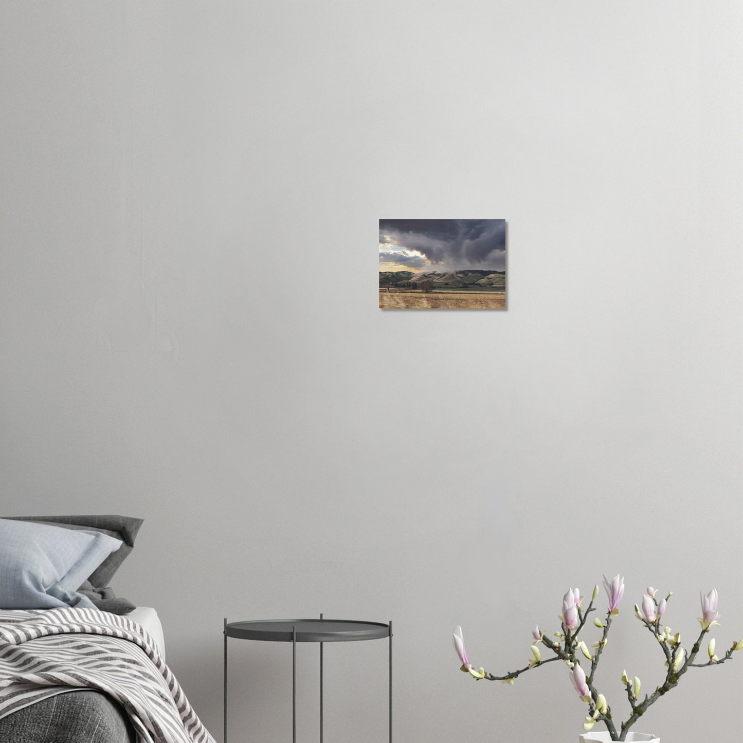 Landscape artwork of Te Hauke hills under dark clouds with beams of light breaking through.