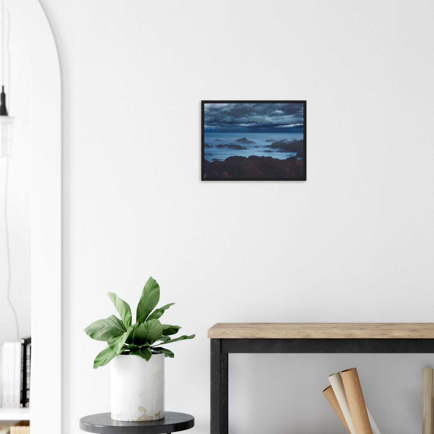 Deep navy and steel-blue tones sweep across a moody sky, while waves crash and swirl around jagged rocks, softened by a misty, dreamlike haze.