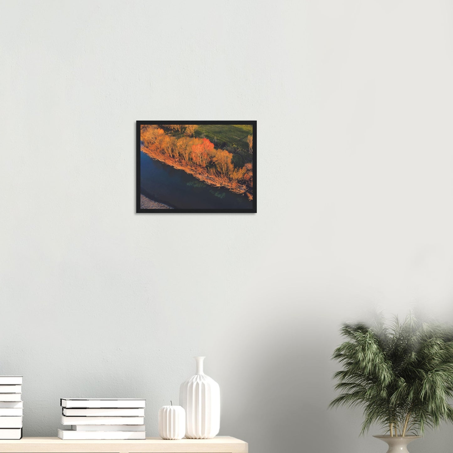 Aerial artwork of autumn trees glowing orange beside a deep blue New Zealand river, full of bold contrast and colour.