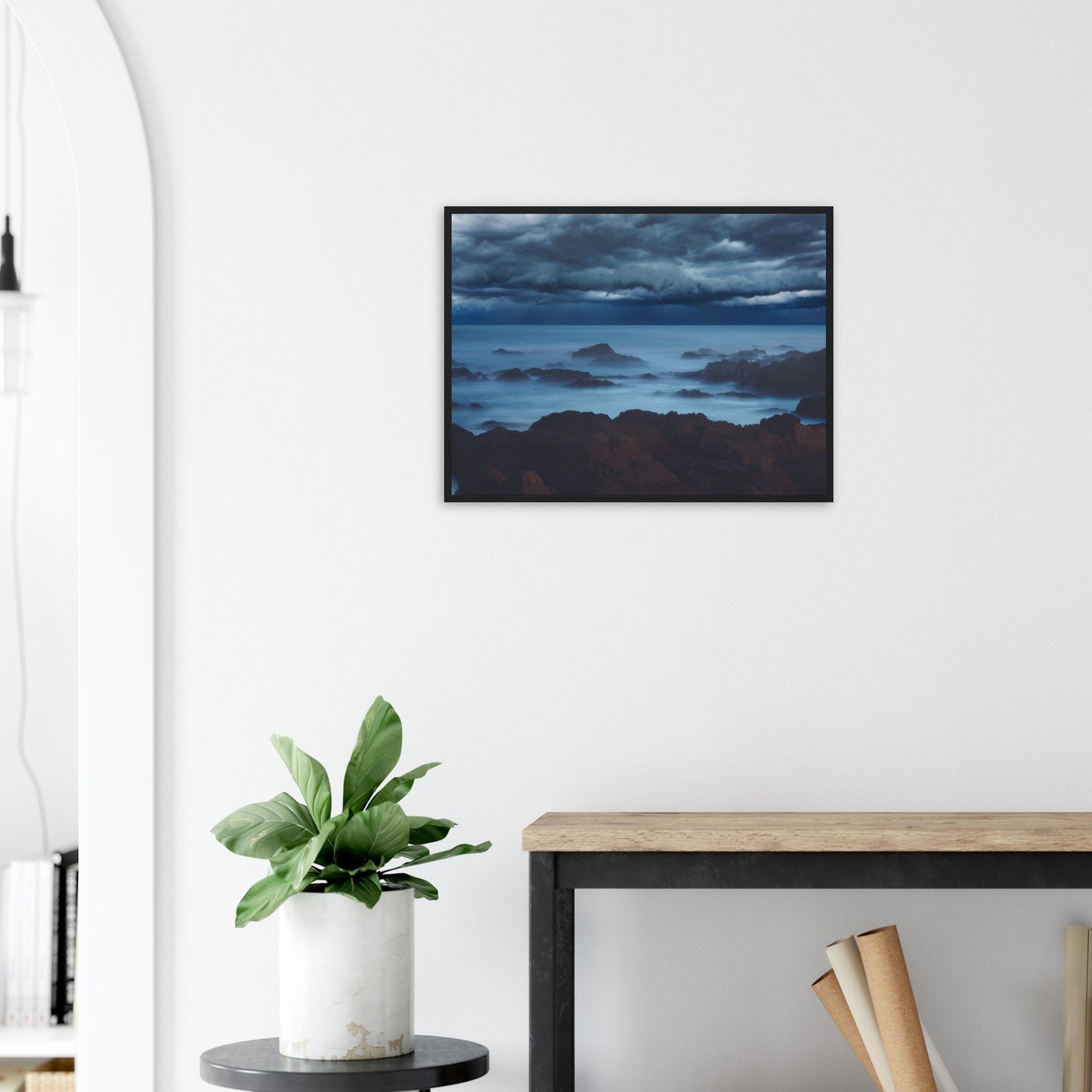 Deep navy and steel-blue tones sweep across a moody sky, while waves crash and swirl around jagged rocks, softened by a misty, dreamlike haze.