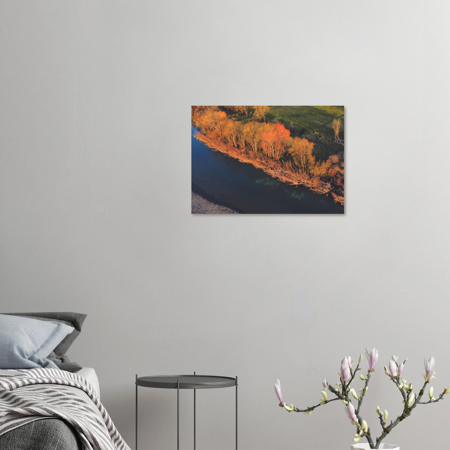 Aerial artwork of autumn trees glowing orange beside a deep blue New Zealand river, full of bold contrast and colour.