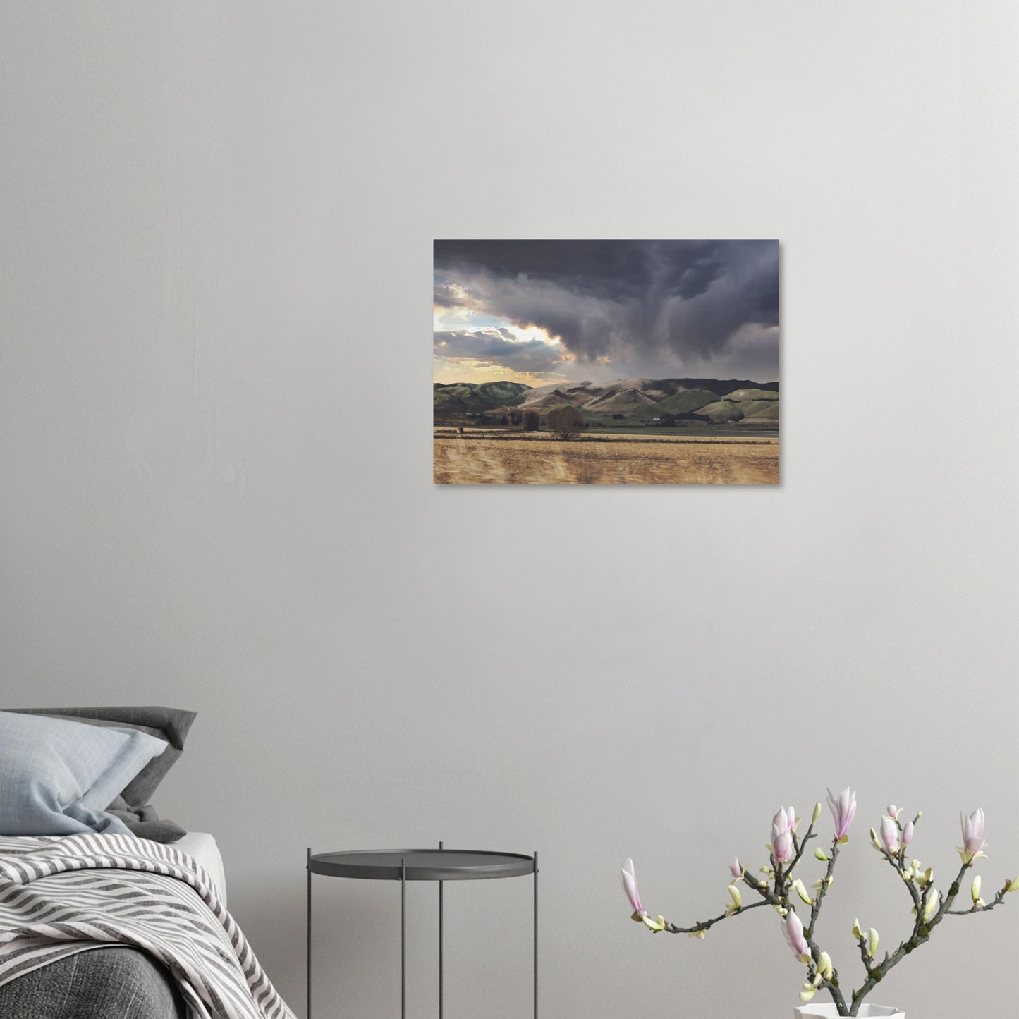 Landscape artwork of Te Hauke hills under dark clouds with beams of light breaking through.