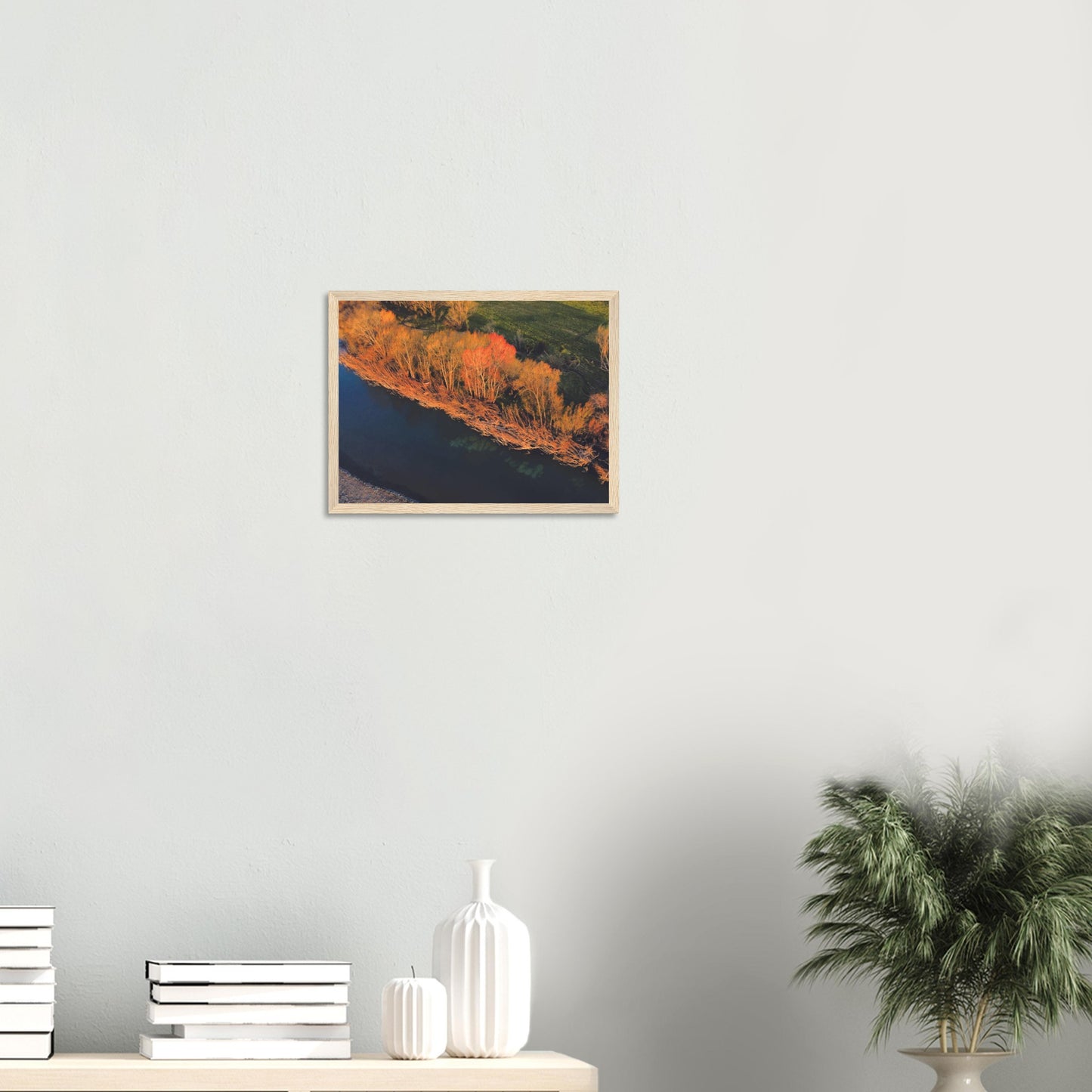 Aerial artwork of autumn trees glowing orange beside a deep blue New Zealand river, full of bold contrast and colour.