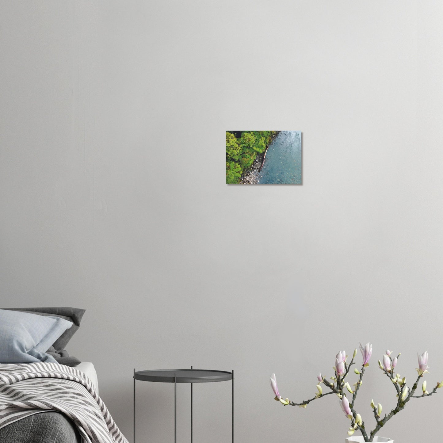 Artwork of native bush and a riverbank viewed from above, with driftwood resting at the water’s edge.