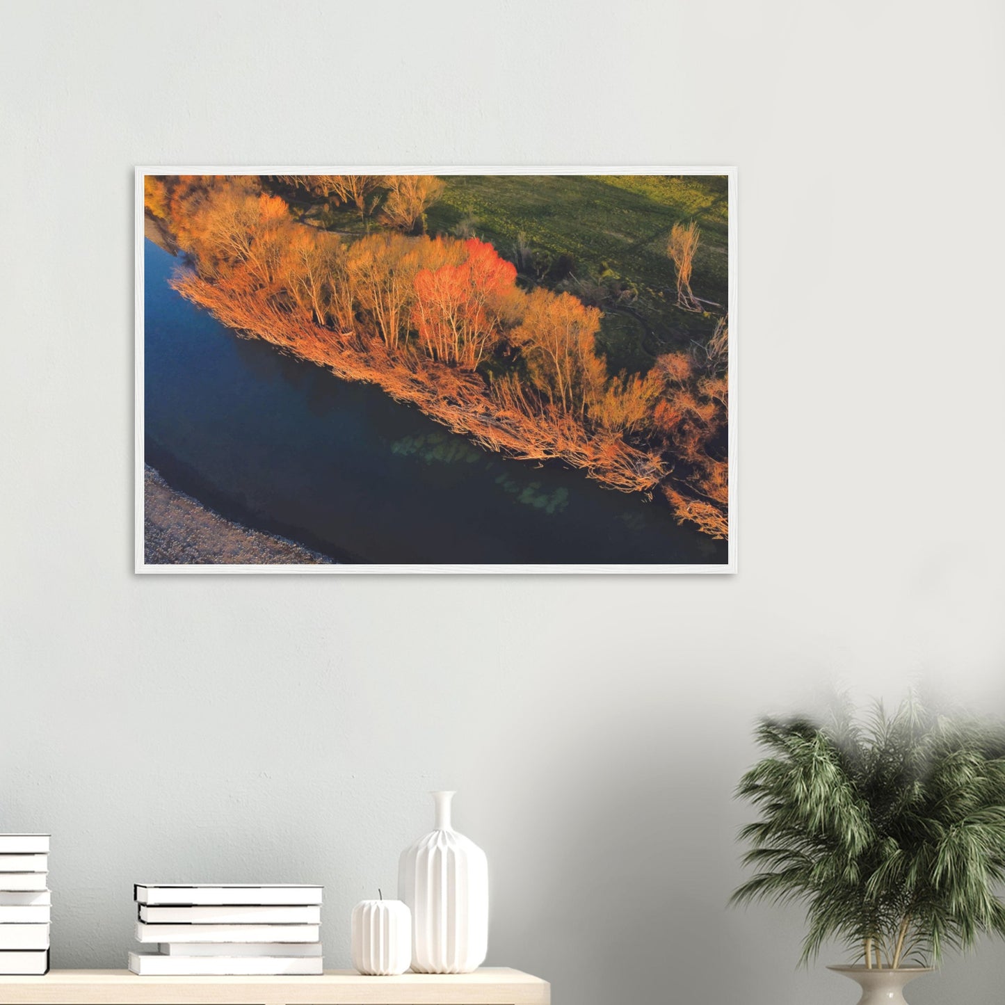 Aerial artwork of autumn trees glowing orange beside a deep blue New Zealand river, full of bold contrast and colour.