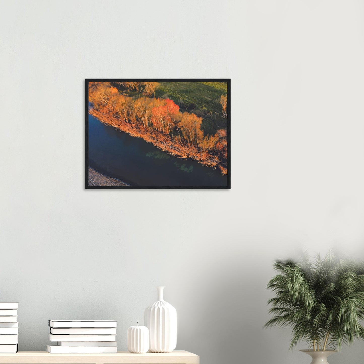 Aerial artwork of autumn trees glowing orange beside a deep blue New Zealand river, full of bold contrast and colour.