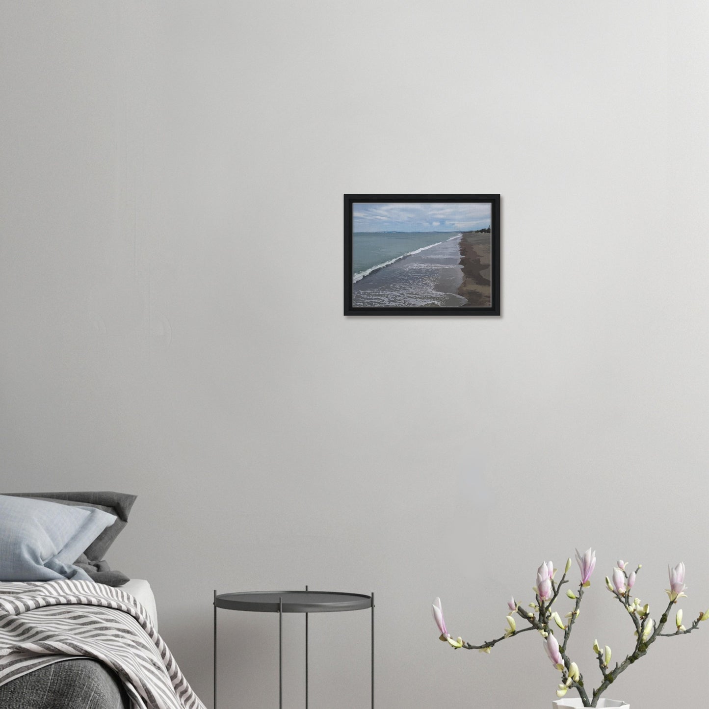 Gentle waves roll onto the dark sand, stretching endlessly into the distance under a softly clouded sky. Hints of pine trees and distant land complete the scene