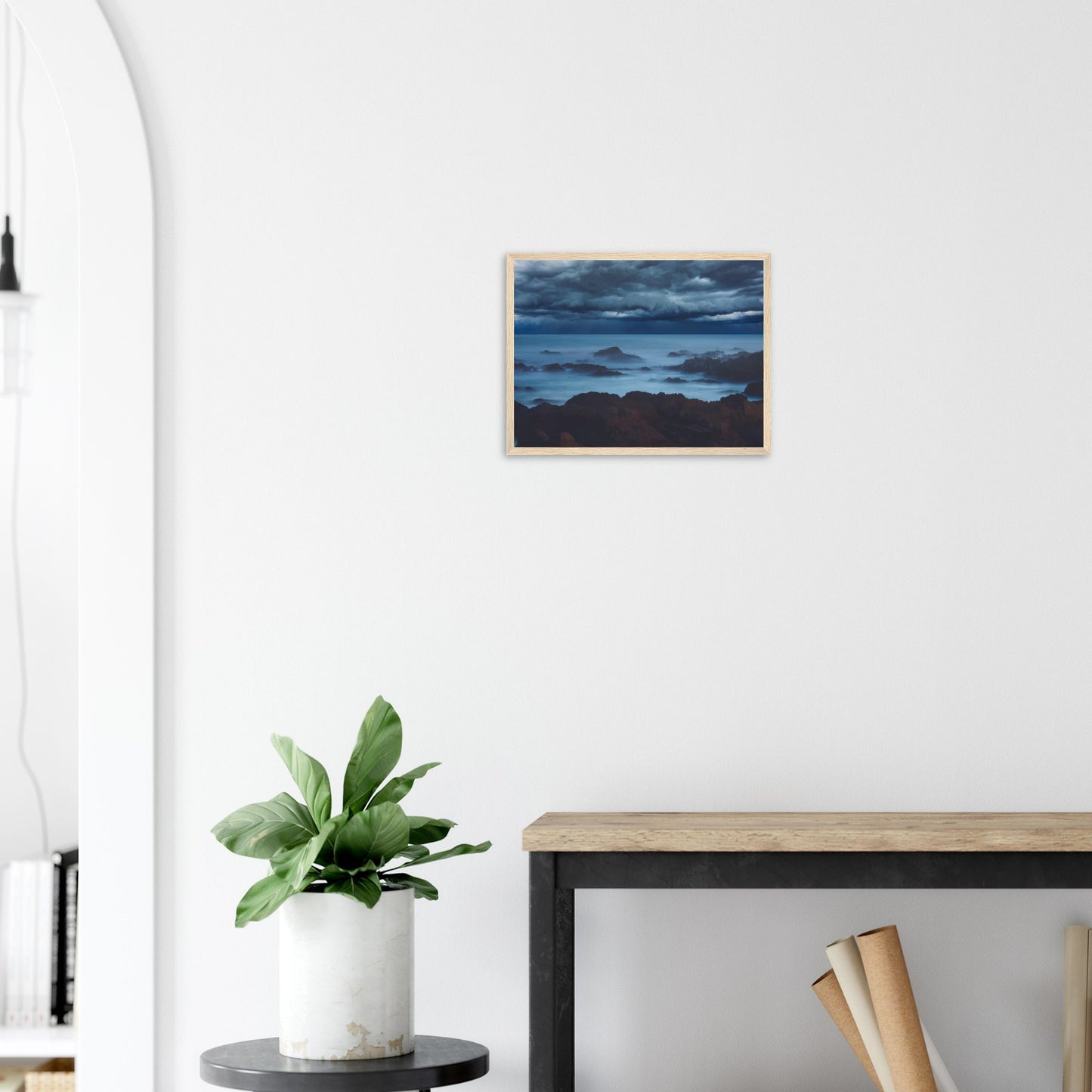 Deep navy and steel-blue tones sweep across a moody sky, while waves crash and swirl around jagged rocks, softened by a misty, dreamlike haze.