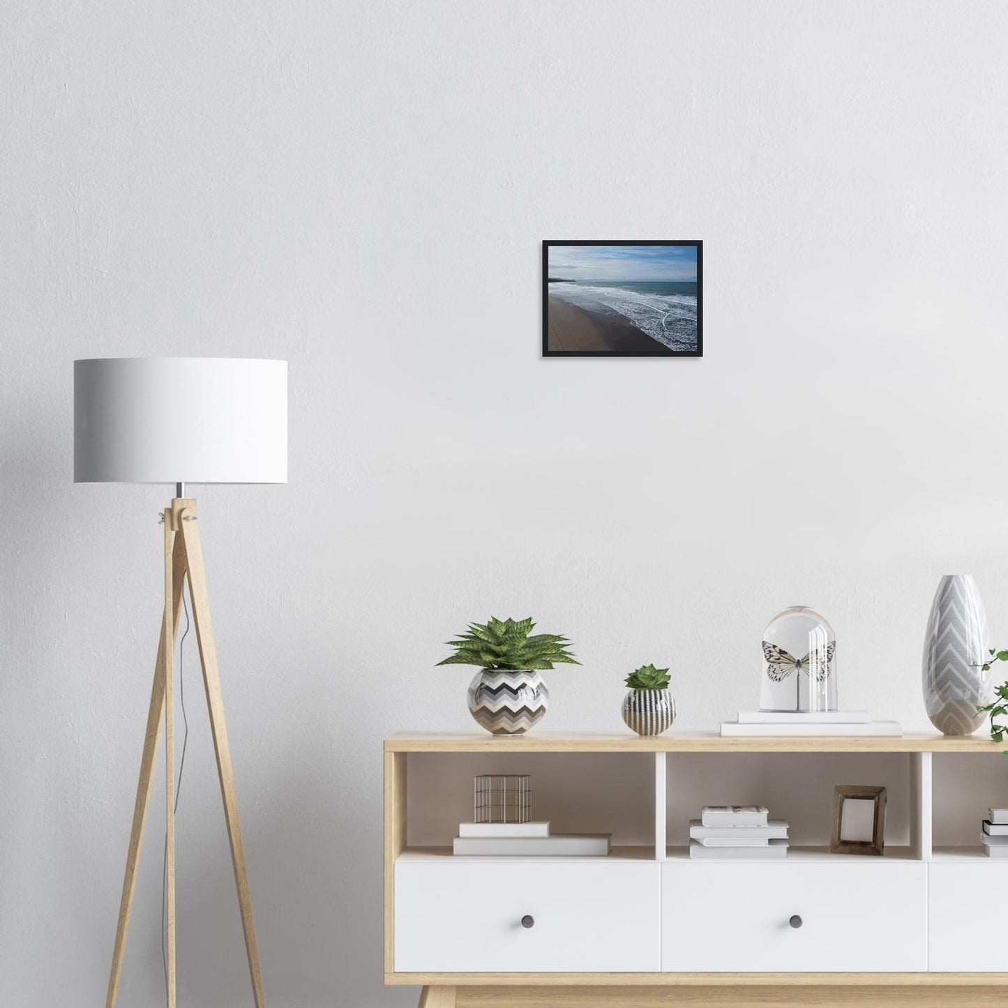 Soft, muted tones of sand, seafoam, and sky blend together in a calming composition, highlighting the natural rhythm of waves lapping the shore.