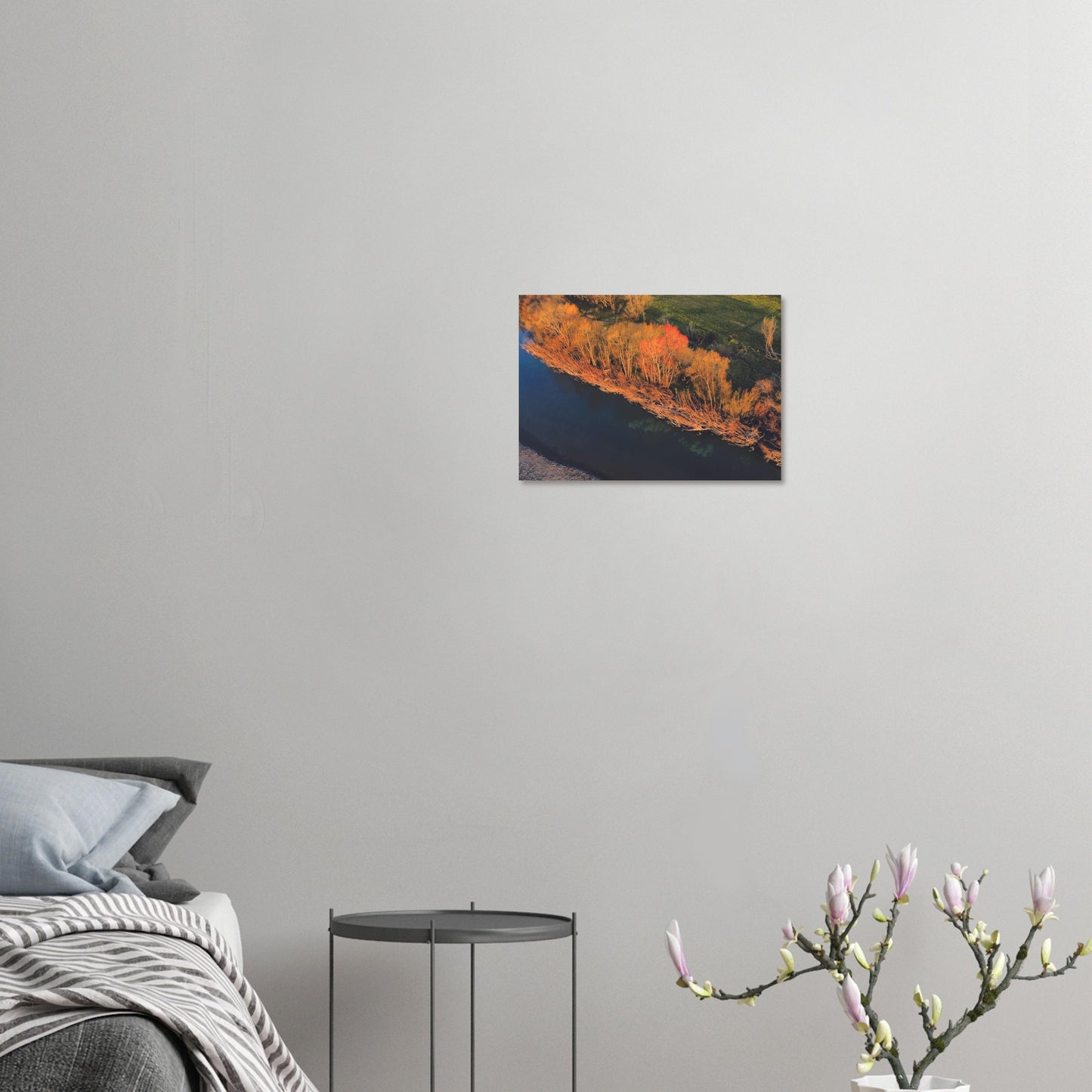 Aerial artwork of autumn trees glowing orange beside a deep blue New Zealand river, full of bold contrast and colour.