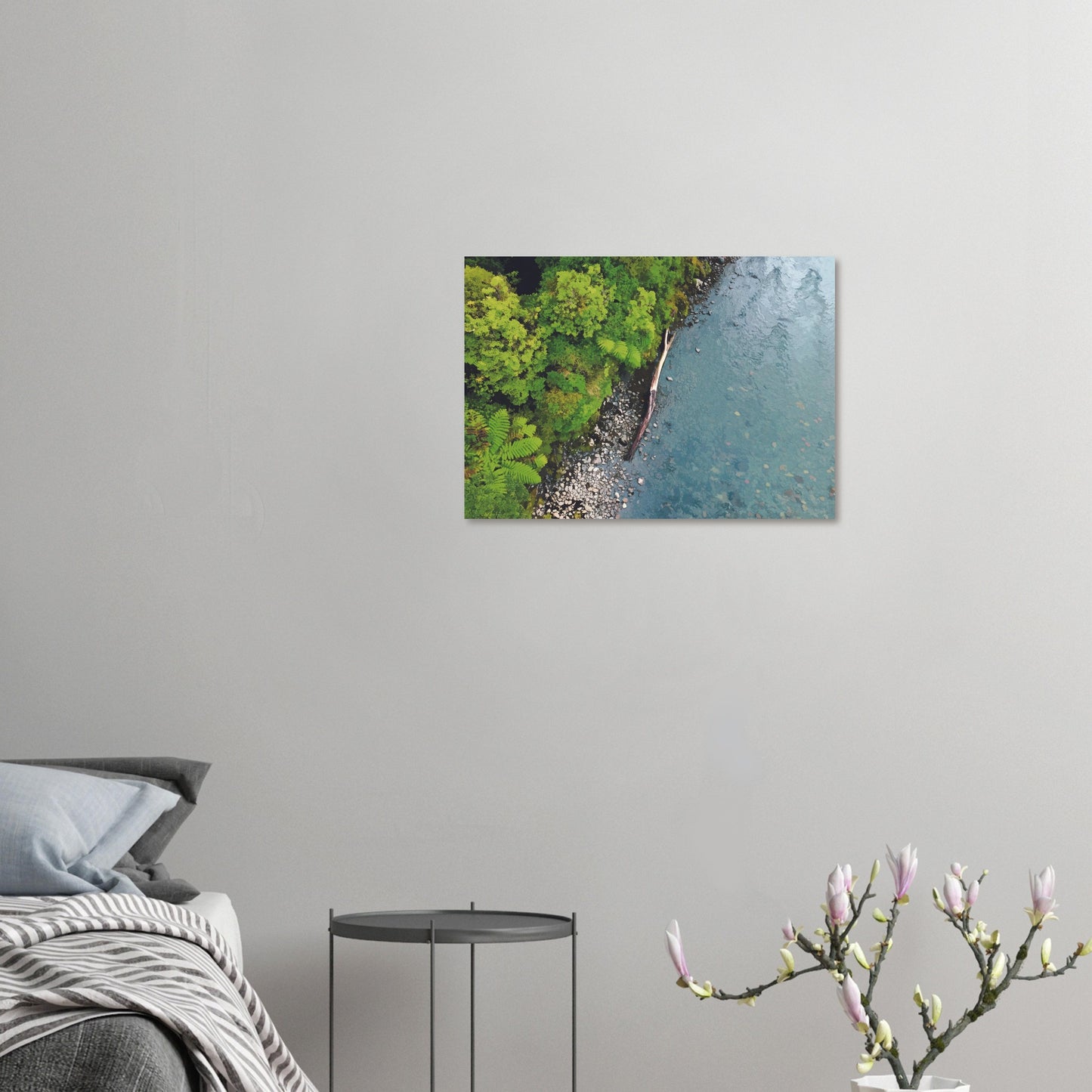 Artwork of native bush and a riverbank viewed from above, with driftwood resting at the water’s edge.