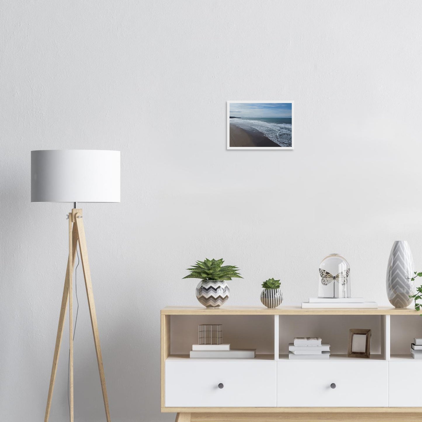 Soft, muted tones of sand, seafoam, and sky blend together in a calming composition, highlighting the natural rhythm of waves lapping the shore.
