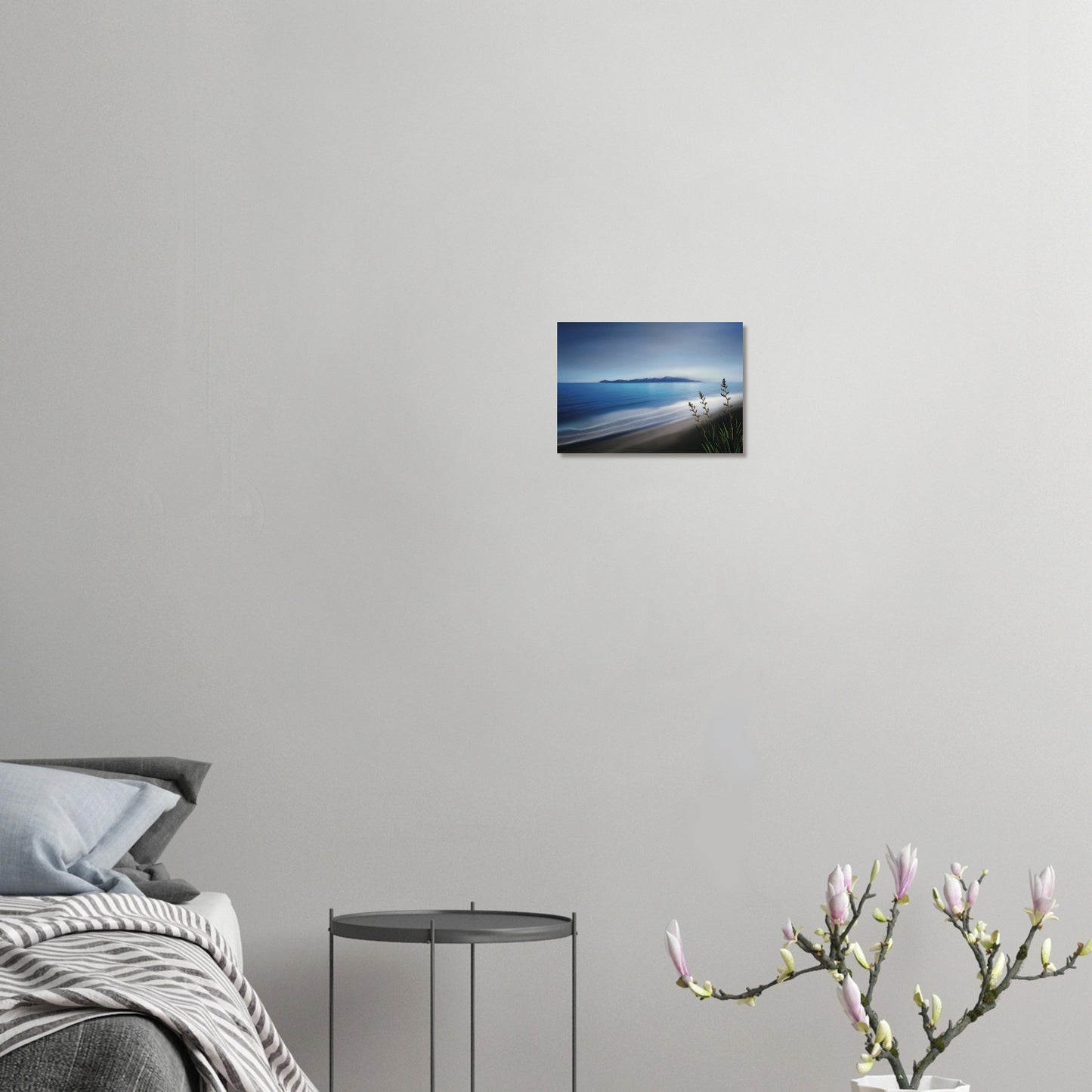 Kapiti Island with soft blue sea, gentle waves and native flax in the foreground.