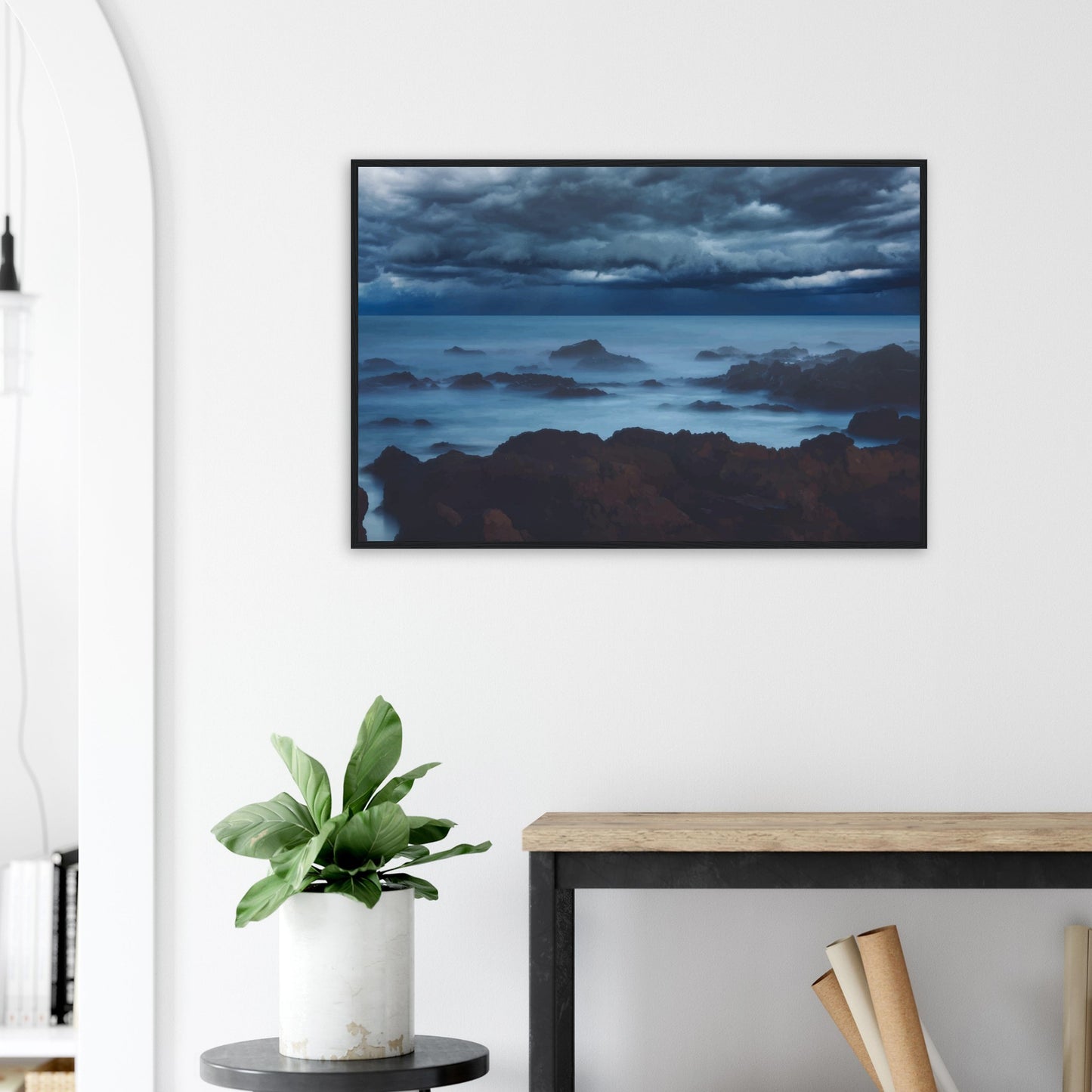 Deep navy and steel-blue tones sweep across a moody sky, while waves crash and swirl around jagged rocks, softened by a misty, dreamlike haze.