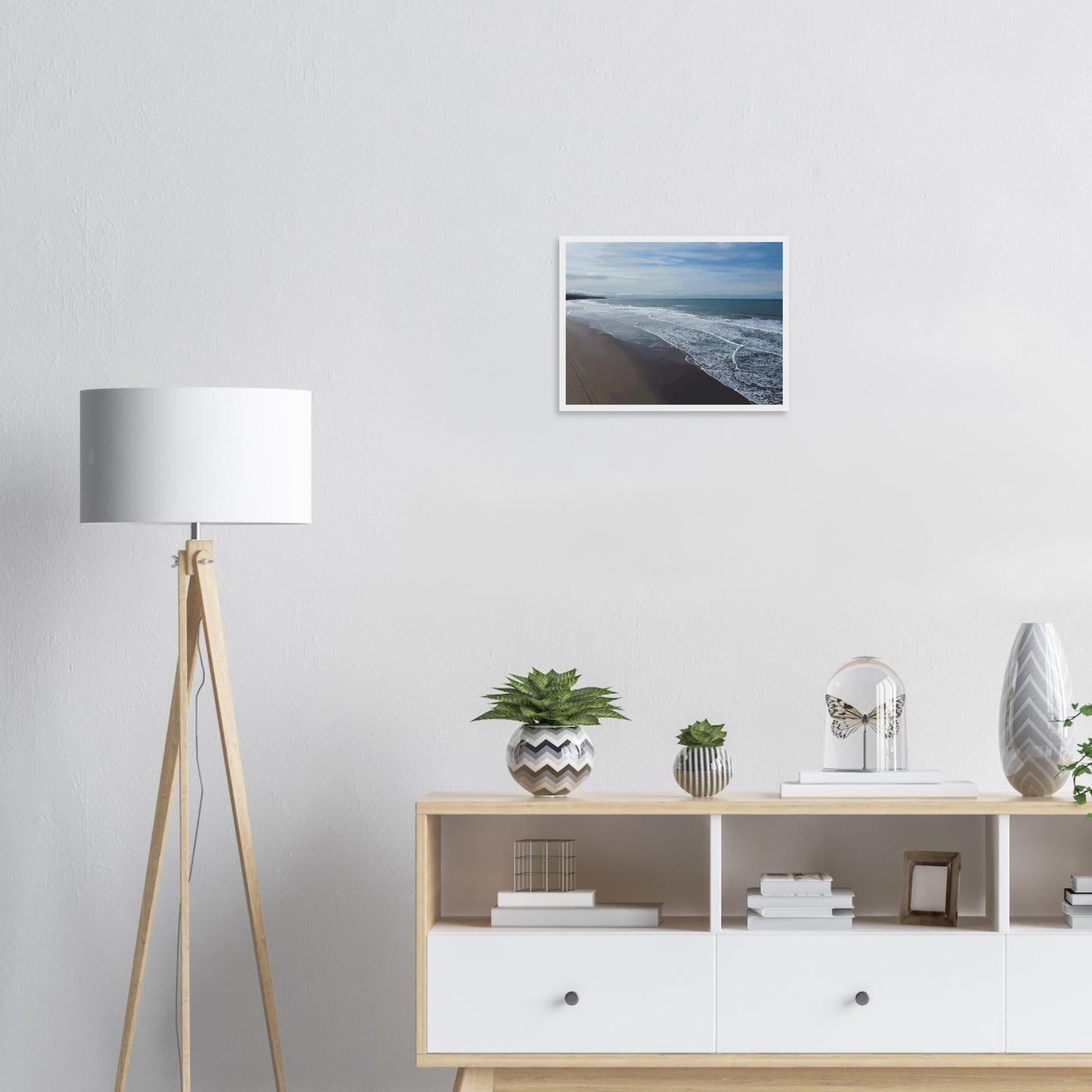 Soft, muted tones of sand, seafoam, and sky blend together in a calming composition, highlighting the natural rhythm of waves lapping the shore.