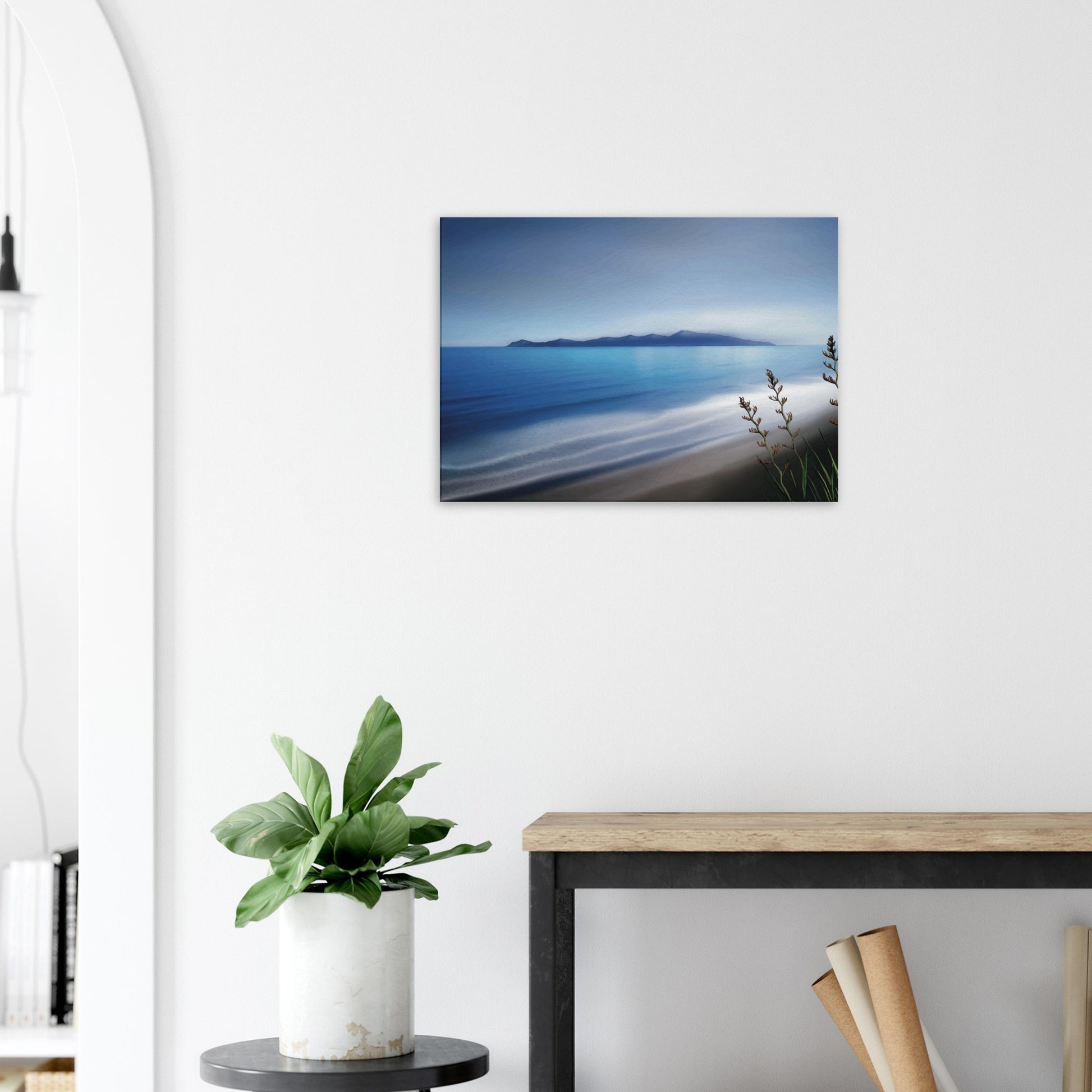 Kapiti Island with soft blue sea, gentle waves and native flax in the foreground.