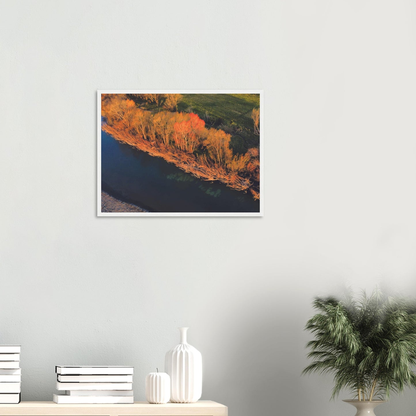 Aerial artwork of autumn trees glowing orange beside a deep blue New Zealand river, full of bold contrast and colour.