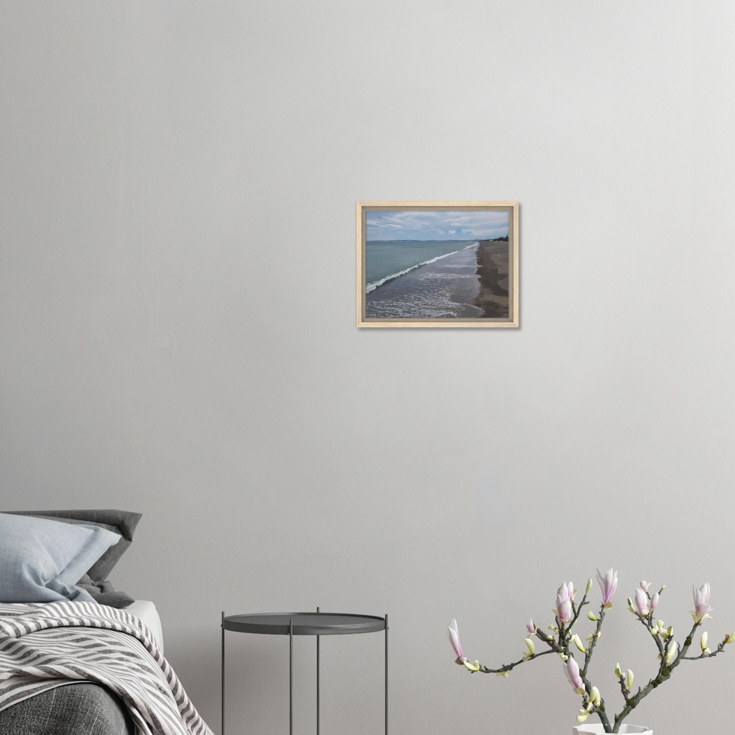 Gentle waves roll onto the dark sand, stretching endlessly into the distance under a softly clouded sky. Hints of pine trees and distant land complete the scene
