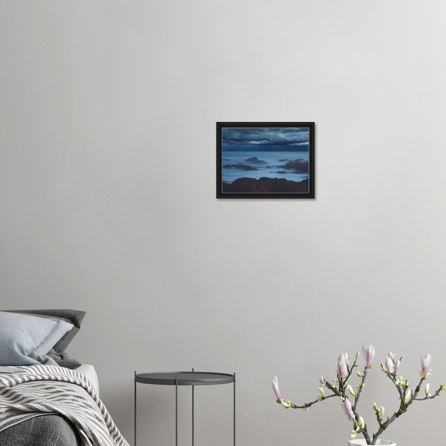 Deep navy and steel-blue tones sweep across a moody sky, while waves crash and swirl around jagged rocks, softened by a misty, dreamlike haze.