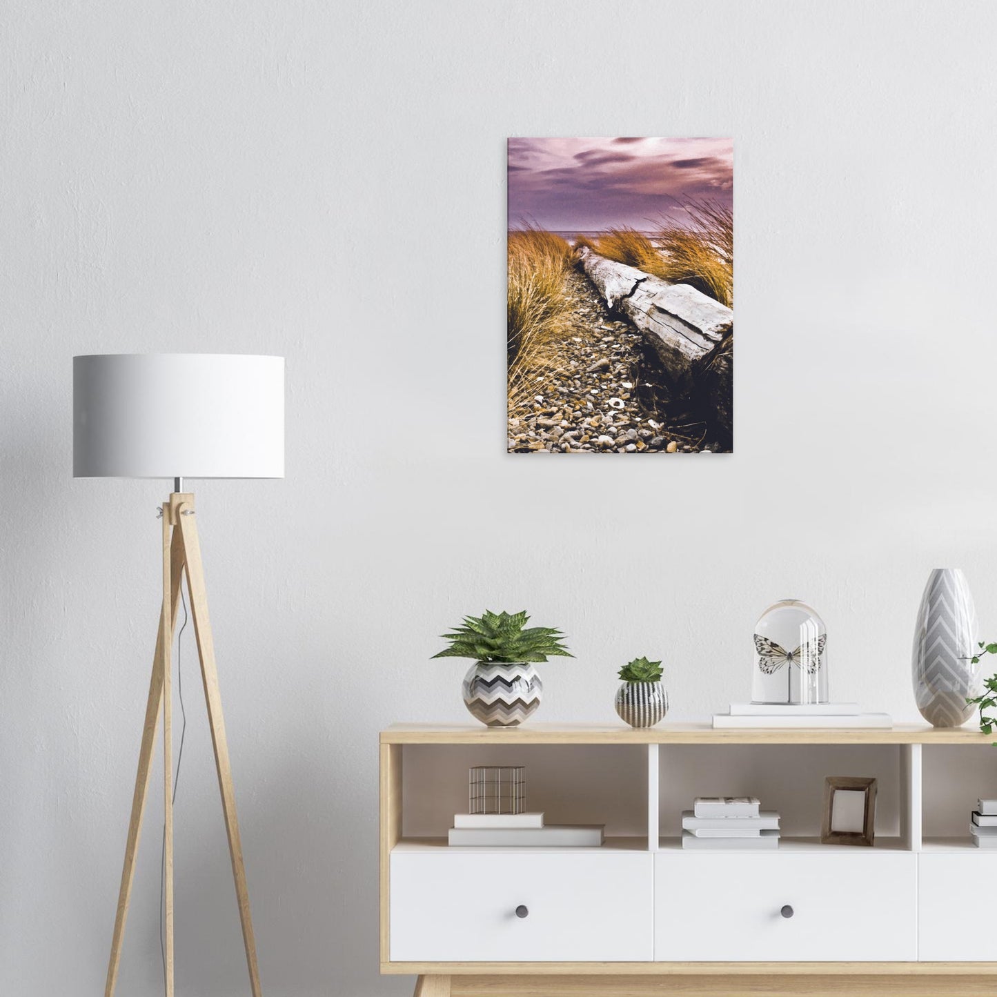 Driftwood lying in coastal grasses under a purple sky, evoking weathered texture and calm.