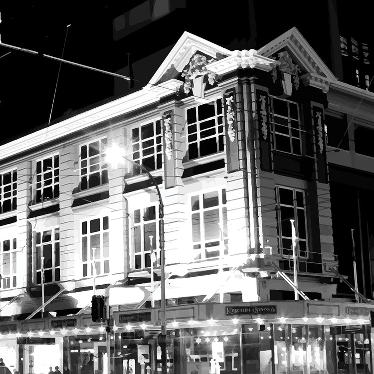 Monochrome artwork of Wellington’s Kirkaldie and Stains building lit at night, showcasing historic architectural details.