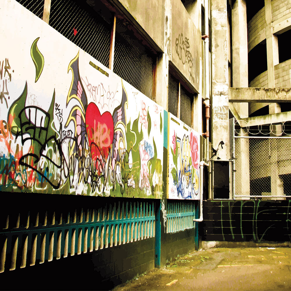 Graffiti-covered alley with concrete walls and fence, full of urban texture and raw colour.