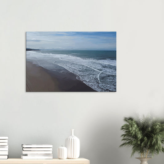 Soft, muted tones of sand, seafoam, and sky blend together in a calming composition, highlighting the natural rhythm of waves lapping the shore.