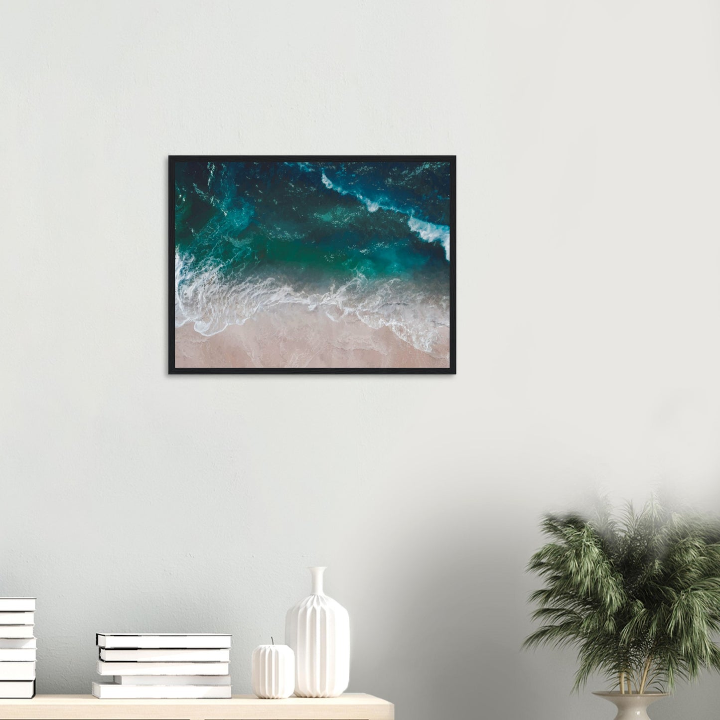 Aerial view of ocean waves rolling onto sand in teal and blue tones.