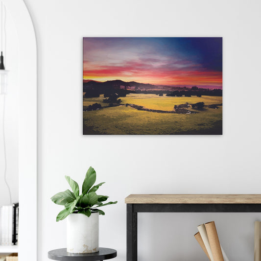 Sunrise over green fields and hills in Wairarapa, with glowing skies in purple, orange, and pink.