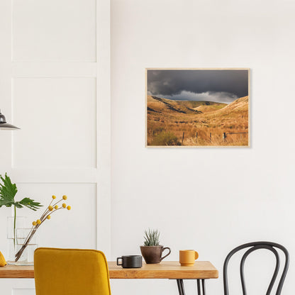 Golden Hawke’s Bay hills beneath dark clouds in a nostalgic NZ landscape artwork titled Trip Home by Ben Hart.