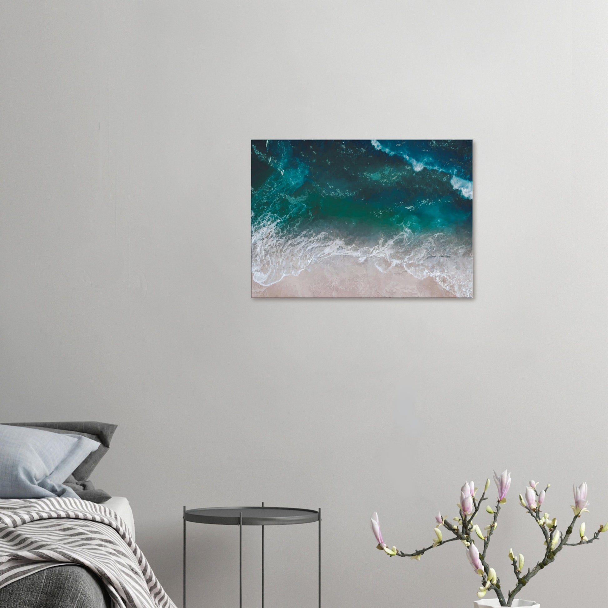 Aerial view of ocean waves rolling onto sand in teal and blue tones.