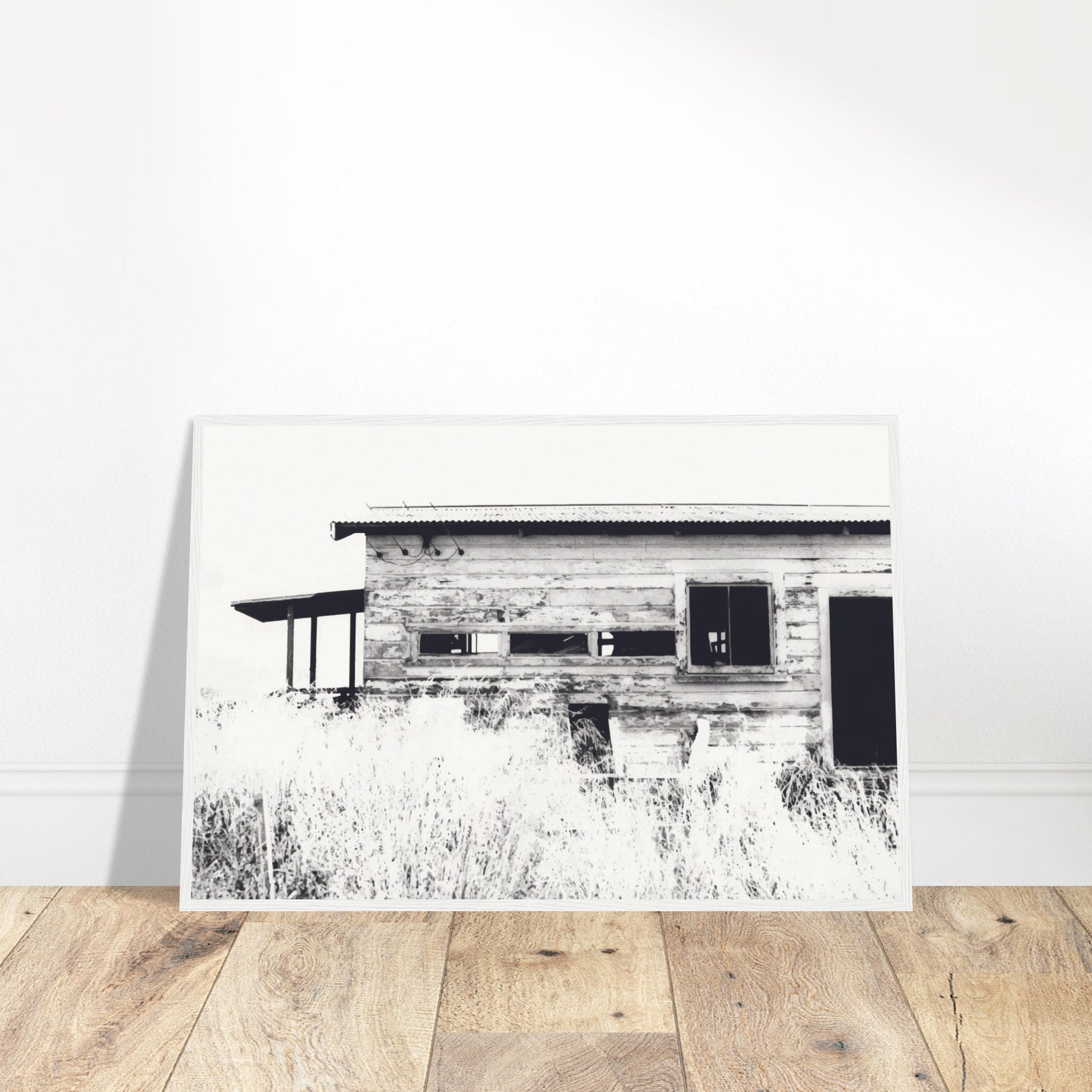 Old timber woolshed in black and white with peeling paint and wild grass in The Woolshed by NZ artist Ben Hart.
