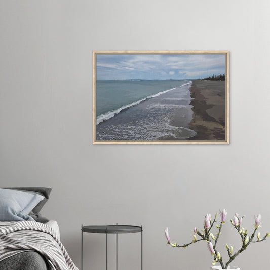 Gentle waves roll onto the dark sand, stretching endlessly into the distance under a softly clouded sky. Hints of pine trees and distant land complete the scene
