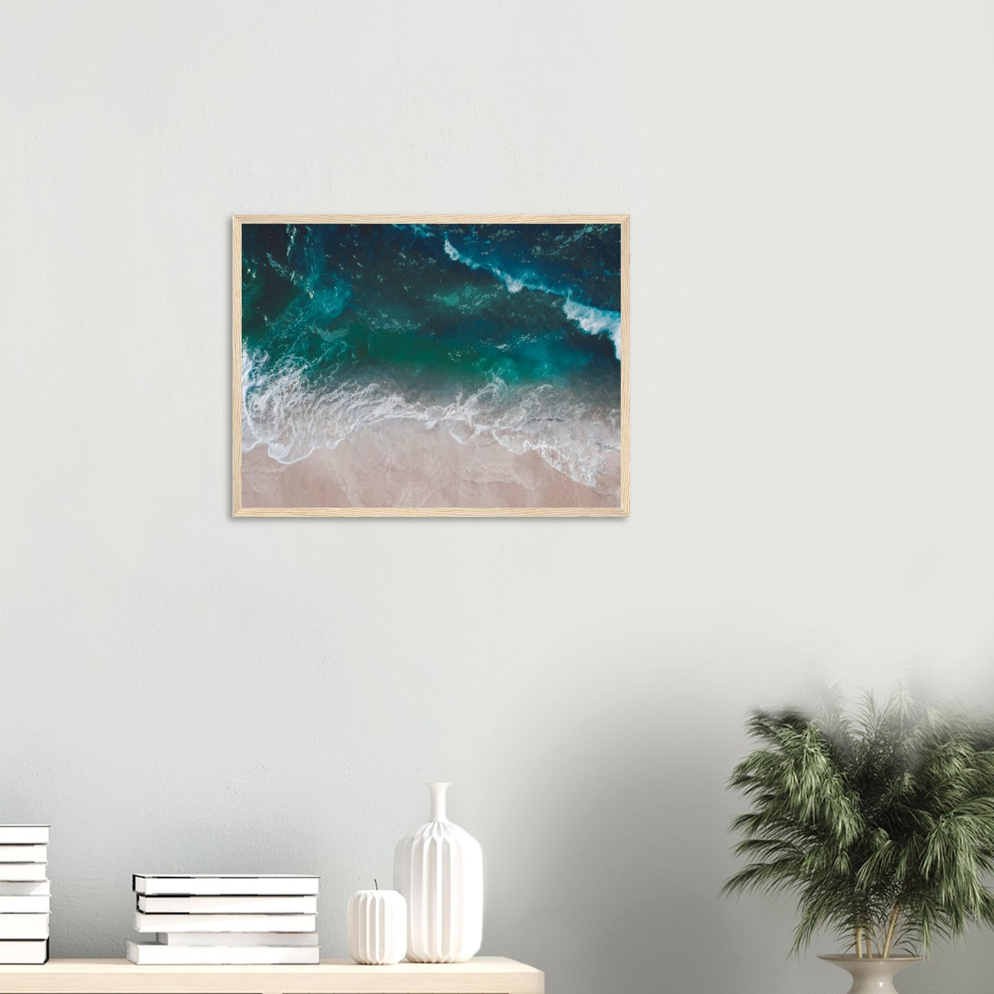 Aerial view of ocean waves rolling onto sand in teal and blue tones.