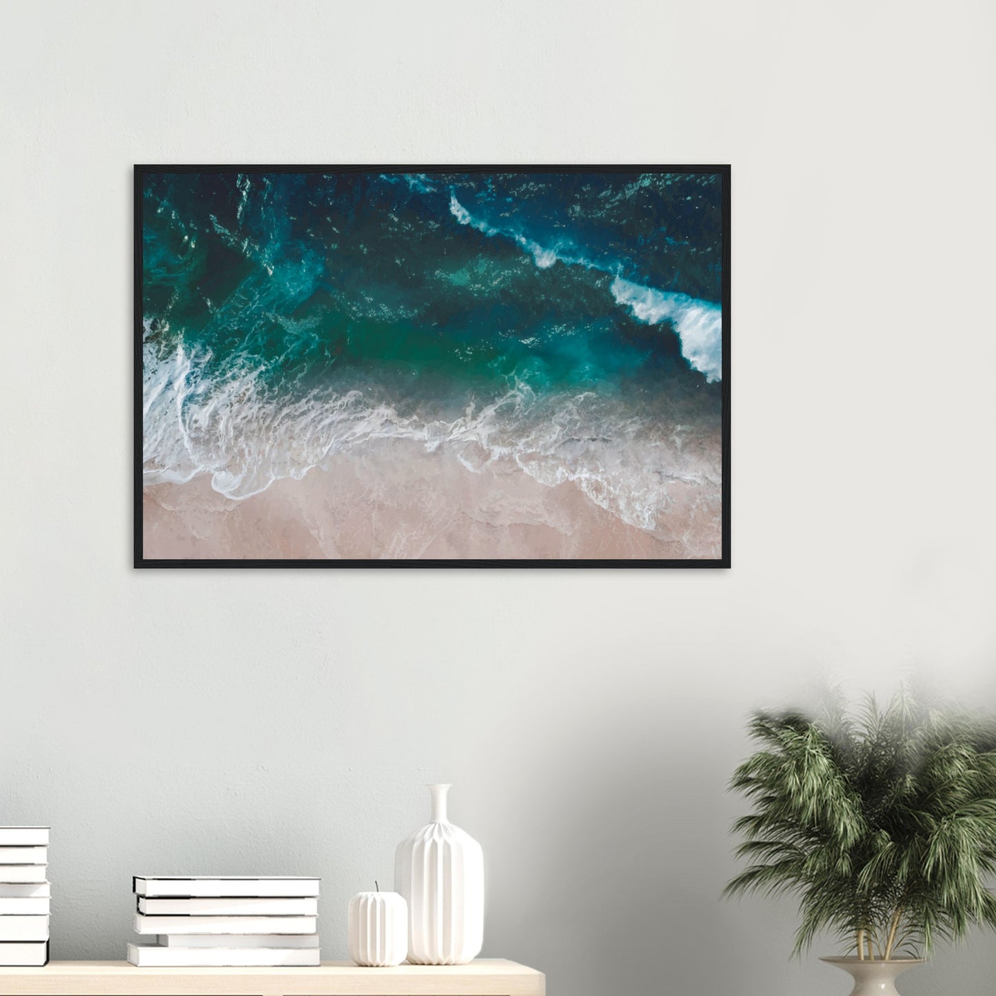 Aerial view of ocean waves rolling onto sand in teal and blue tones.