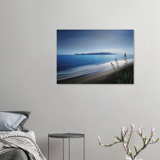 Kapiti Island with soft blue sea, gentle waves and native flax in the foreground.