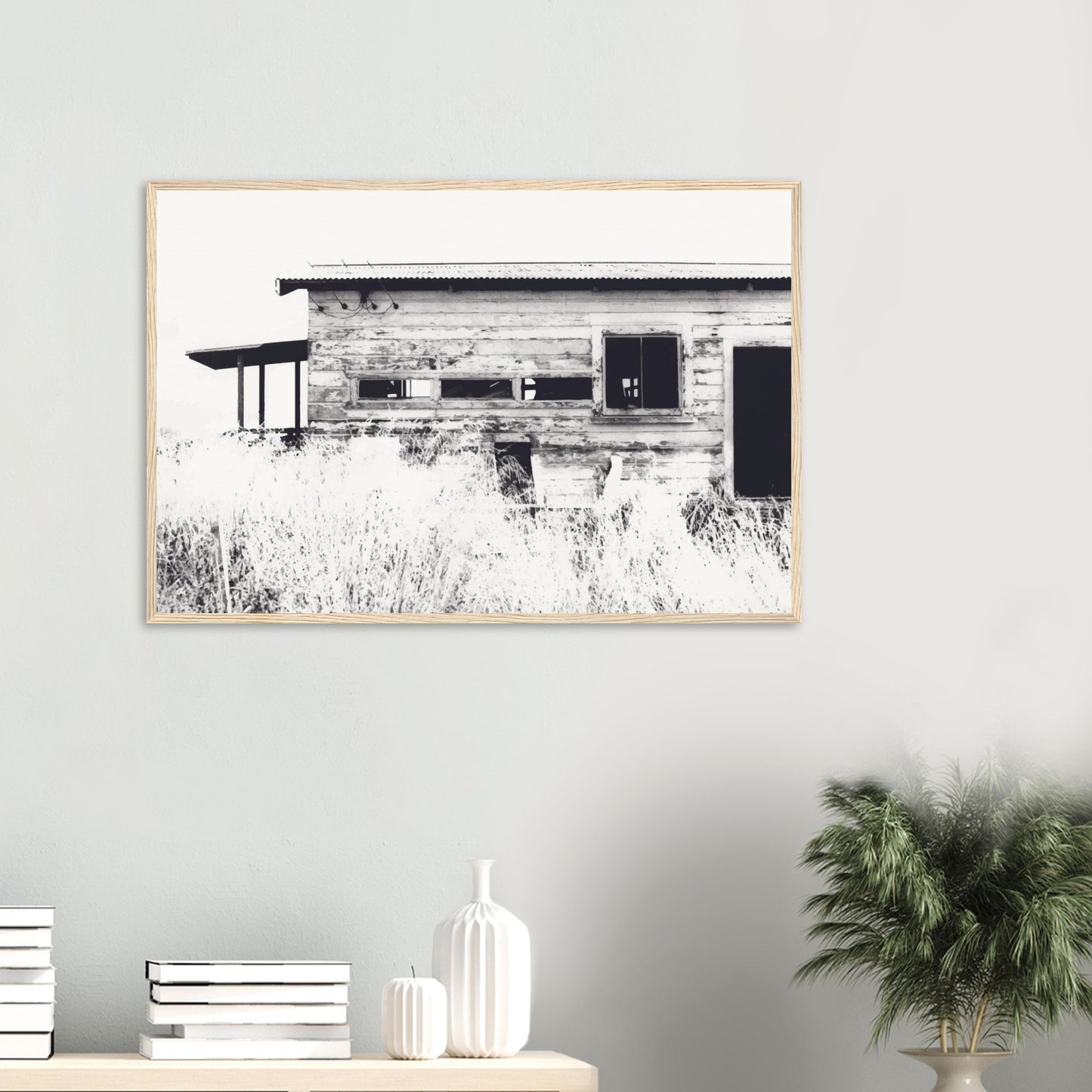 Old timber woolshed in black and white with peeling paint and wild grass in The Woolshed by NZ artist Ben Hart.