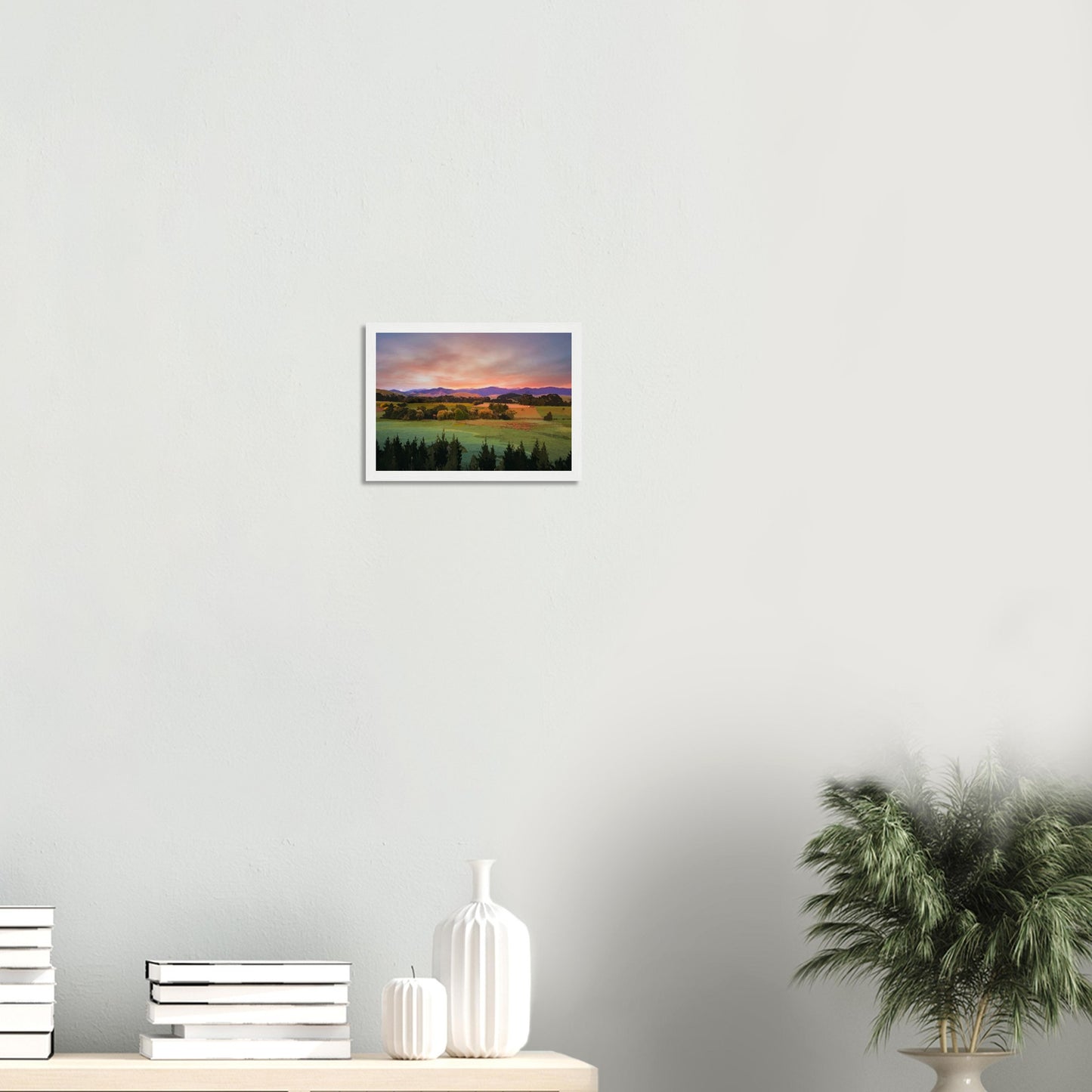 Artwork of a Wairarapa sunrise over pine trees and rolling farmland with soft light on the Tararua Ranges.