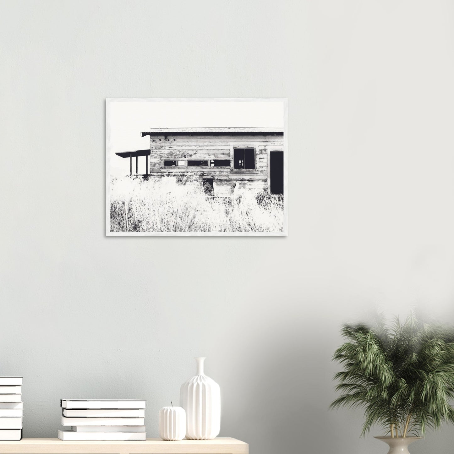 Old timber woolshed in black and white with peeling paint and wild grass in The Woolshed by NZ artist Ben Hart.