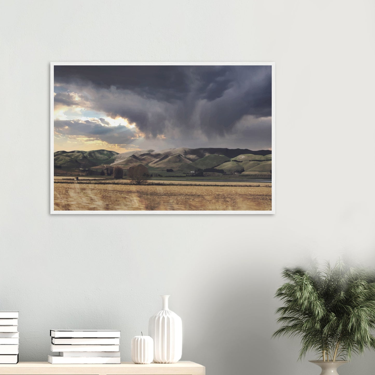 Landscape artwork of Te Hauke hills under dark clouds with beams of light breaking through.