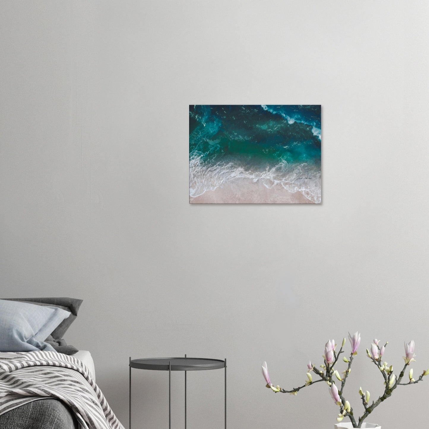 Aerial view of ocean waves rolling onto sand in teal and blue tones.