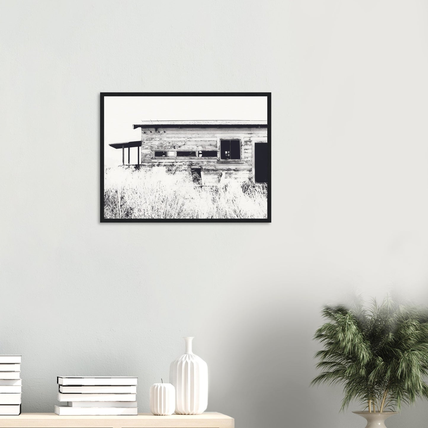 Old timber woolshed in black and white with peeling paint and wild grass in The Woolshed by NZ artist Ben Hart.