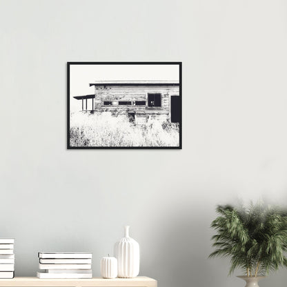 Old timber woolshed in black and white with peeling paint and wild grass in The Woolshed by NZ artist Ben Hart.