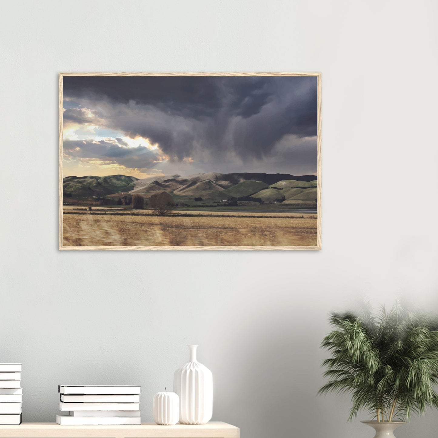 Landscape artwork of Te Hauke hills under dark clouds with beams of light breaking through.
