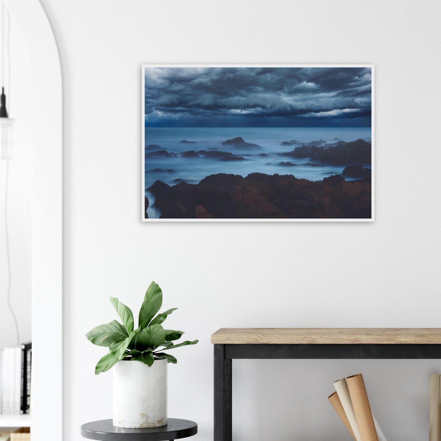 Deep navy and steel-blue tones sweep across a moody sky, while waves crash and swirl around jagged rocks, softened by a misty, dreamlike haze.