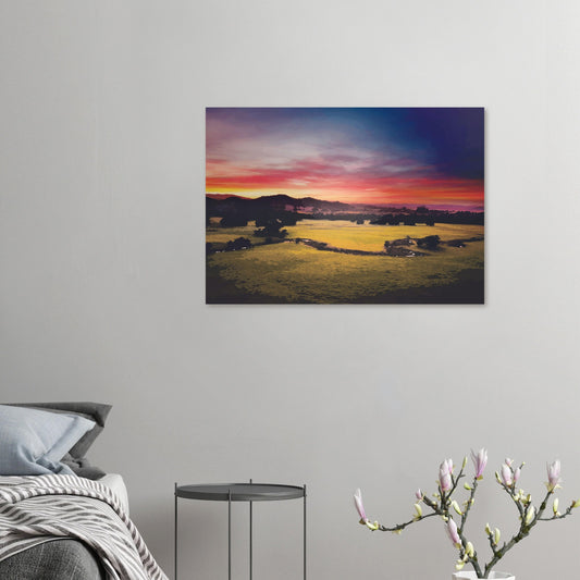Sunrise over green fields and hills in Wairarapa, with glowing skies in purple, orange, and pink.